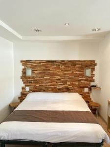 a bedroom with a bed with a brick wall at Hôtel Beau Soleil in Le Lavandou
