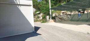 eine Garage neben einem Gebäude mit Parkplatz in der Unterkunft Apartman Eva Rogotin in Rogotin