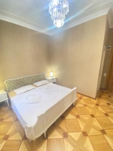 a bedroom with a white bed and a chandelier at K&N Guesthouse in Tbilisi City