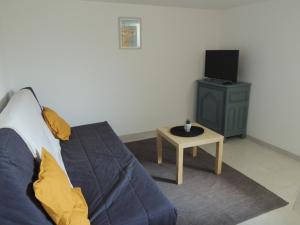 een woonkamer met een bank, een tv en een tafel bij Appartement entre terre et baie in Pontorson