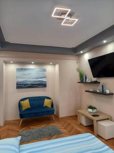 sala de estar con sofá azul y TV de pantalla plana en Zenit Apartman, en Makó