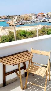 un banco de madera sentado en un balcón con vistas al puerto en Il maestro di nodi - Casa vista mare, en Lampedusa
