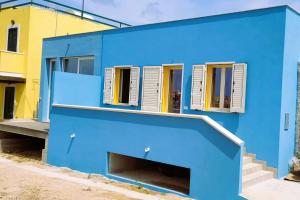 a blue building with white shutters on it at Il maestro di nodi - Casa vista mare in Lampedusa