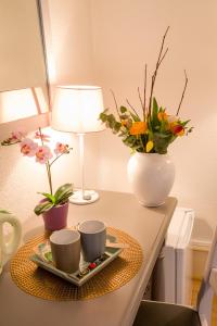 un tavolo con due tazze e un vaso con fiori di Chambres Chez Laurence a Kaysersberg