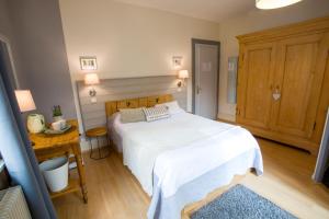 a bedroom with a white bed and a wooden desk at Chambres Chez Laurence in Kaysersberg