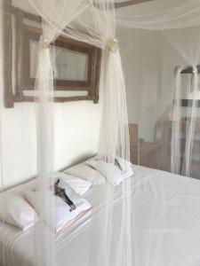 Una cama con mosquiteros blancos encima. en LES ALOÈS By CREYOL ANIMAL, en Grand-Bourg