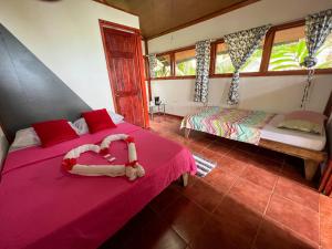 a bedroom with two beds with pink sheets and windows at Corcovado Adventures in Drake