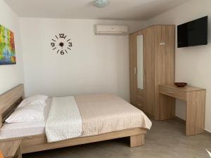 sypialnia z łóżkiem i zegarem na ścianie w obiekcie Dajkovic Apartmani w Barze