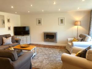 a living room with couches and a flat screen tv at Limekiln Cottage in Llanasa