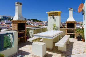 uma varanda com uma mesa e bancos num telhado em Edifício Tomás em Ferragudo