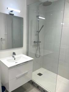 La salle de bains blanche est pourvue d'une douche et d'un lavabo. dans l'établissement APPARTEMENT LE ROUSSEAU METZ AVEC PARKING GRATUIT, à Metz