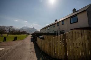 a fence in front of a house and a field at Annie's Corner - Fort William in Caol