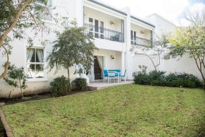 a white house with a lawn in front of it at Maison Des Huguenots Le Roux in Franschhoek