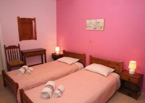 two beds in a room with pink walls at Kantouni House Kefalonia in Argostoli