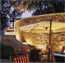 a stone wall with a table and an umbrella at Logis Hôtel Restaurant du Moulin in Ligneuville +33 photos