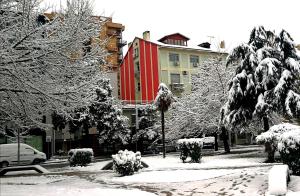 een met sneeuw bedekte straat met gebouwen en bomen bij Central Loft in Tirana
