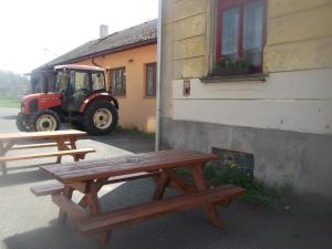 two picnic tables next to a building with a tractor at Restaurace s ubytováním in Křižany