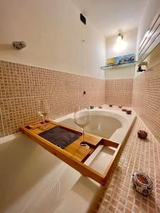 un bagno con vasca e bicchiere di vino di MARMORE HOUSE a Collestatte