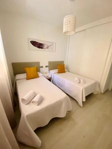 2 bedden in een kamer met witte en oranje kussens bij Apartamento El Mentiro in Cabopino