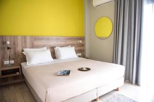 a bedroom with a white bed with a yellow wall at Plakias Riviera in Plakias