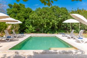 a swimming pool with chairs and umbrellas at FINCA RELAX IBIZA STILE in Sant Josep de sa Talaia