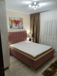 1 dormitorio con 1 cama grande y cabecero rosa en Sunrise Home Apartment en Mangalia