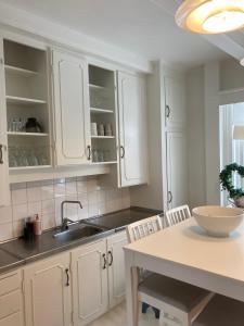 a kitchen with white cabinets and a sink and a table at Bulls Haven Villa Kristiansand in Kristiansand