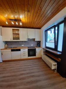 Il comprend une cuisine avec des placards blancs et un plafond en bois. dans l'établissement 2-Zimmer Ferienwohnung-Einklang im schönen Südschwarzwald, à Todtnau