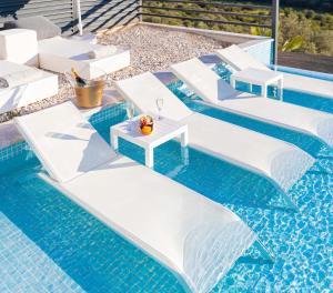 a pool with white chairs and a table in the water at Luxury Villa for 8 with 20m large Infinity Pool in Kalkan in Kaş