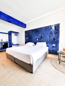 a large bed in a bedroom with a blue wall at Pen&eacute;lope Hotel in Ialyssos