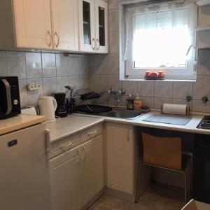 uma cozinha com armários brancos, um lavatório e uma janela em Monro Apartment em Hévíz