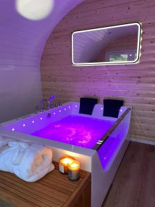a bathroom with a purple tub with candles and lights at Apex Studio Pod & Jacuzzi Bath in Fort William