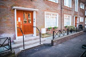 a brick building with an orange door and stairs at Aunt Mary's in Belfast