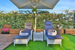 zwei Stühle und ein Regenschirm auf einem Rasen in der Unterkunft Hotel Tigullio Et De Milan in Santa Margherita Ligure