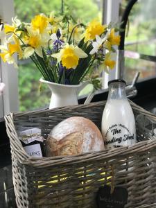 Una cesta con flores y pan y un jarrón de flores. en Coombe Cottage en Honiton