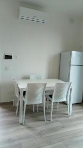 a white table and chairs and a white refrigerator at Riccio di Mare in Lacona