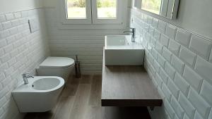bagno bianco con servizi igienici e lavandino di Riccio di Mare a Lacona