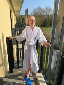 un homme debout sur une terrasse couverte en peignoir blanc dans l'établissement Villa Thermae Santenay, à Santenay