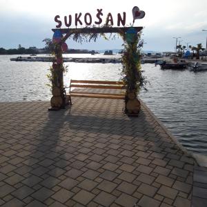a bench with a sign that reads suzukiann next to the water at Apartments Draga in Sukošan