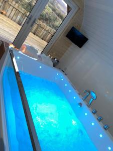 Una gran bañera azul en una habitación con ventana en Apex Studio Pod & Jacuzzi Bath, en Fort William