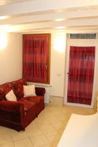salon z kanapą i czerwonymi zasłonami w obiekcie CHIARA HOUSE VENICE w Wenecji