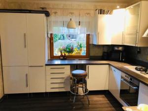 a kitchen with white cabinets and a stool in it at Waldidyll in Neuzelle