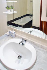 een badkamer met een wastafel, een spiegel en een bad bij Edifício Tomás in Ferragudo
