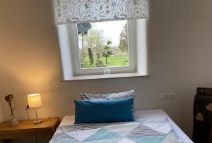 een slaapkamer met een raam en een bed met een blauw kussen bij Ferienwohnung Roth, Unlingen in Unlingen