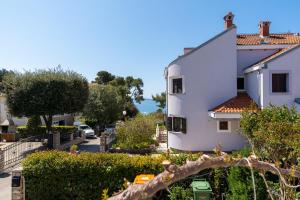 a white building next to a street with trees at Apartment Nada in Petrcane