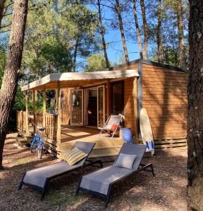 une cabane dans les bois avec des chaises et une terrasse couverte dans l'établissement Espace Blue Océan, à Ondres
