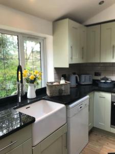 a kitchen with a white sink and a window at Coombe Cottage in Honiton