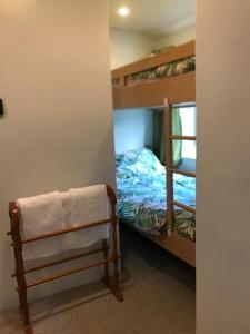 a room with two bunk beds and a bench with a towel at Coombe Cottage in Honiton