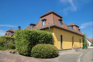 ein gelbes Haus mit einem Steinkamin und Büschen in der Unterkunft Les Bains de Rosheim in Rosheim