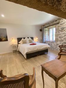 1 dormitorio con cama y pared de piedra en Domaine de Kerdavid - Chambres d'hôtes à Remungol, en Évellys